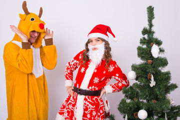 Happy young woman in santa claus hat and man in carnival costume of deer. Fun, holiday, joke and christmas concept