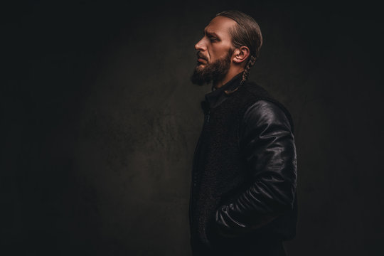 Profile of a fashionable bearded male in a black jacket. Isolated on dark textured background.
