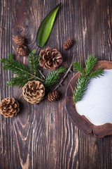 Christmas composition. Ceramic plate, cones and christmas tree branches on a brown wooden background. Top view, free space