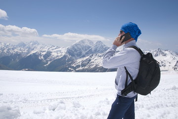 Fototapeta na wymiar Young man talking on the phone among the snowy peaks