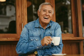 Cheerful senior man having coffee at cafe