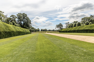 Fototapeta na wymiar Beautiful view of a neat lawn with hedges on the sides in blickling hall, on a sunny day