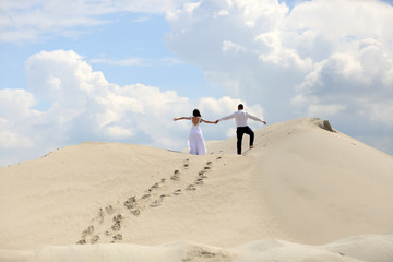 Para młodych ludzi, dziewczyna i chłopak na szczycie piaszczystej wydmy, ślub, wesele.
