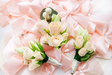  boutonniere for the groom and groomsmen on the background of pink bows made of cloth