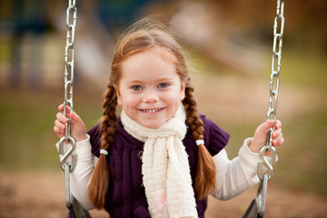 Happy Little Girl on Swing in Autumn