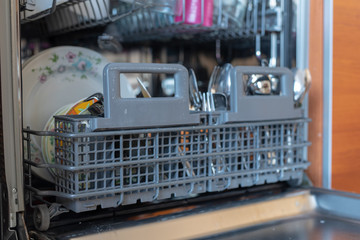 Dishwashing machine filled with dishes. Kitchen appliances helpful in home-made households.