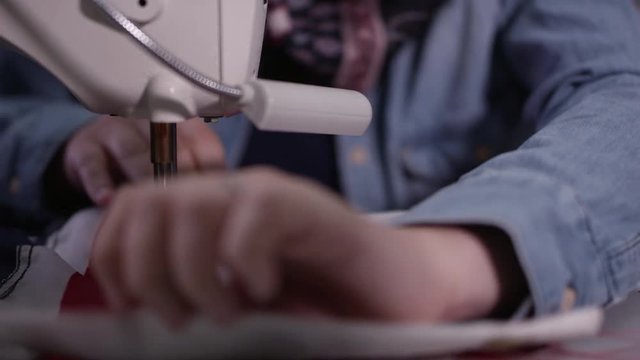 Up close view of hands feeding flag throug sewing machine stiching it together in production.