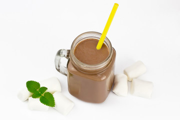 Glass jar with cocoa or hot chocolate, yellow straw, marshmallow, branch of mint on white background