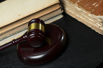 Judge gavel beside pile of books on wooden background