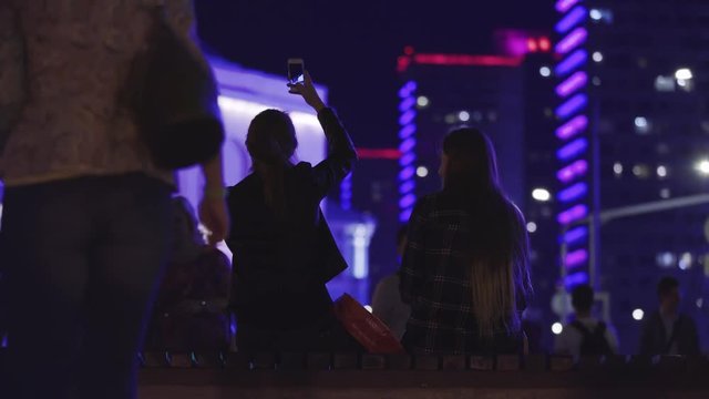 4K Female friends pull silly faces during a selfie in the city at night