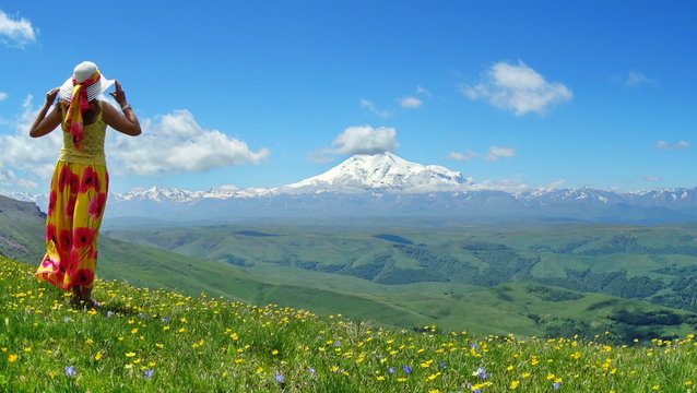 A Woman In A Colorful Skirt And A Yellow Blouse Looks At The Snowy Top