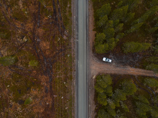 Finland, aerial view of a car parked by the side of the road in the forest of Lapland