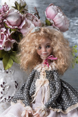 Doll on the table and a vase with peonies.