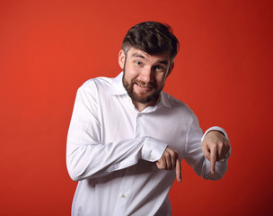 Happy excited bearded business man in white shirt pointing down the finger on red background with empty space background. Closeup portrait