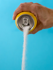Hand holding soda can pouring lots of sugar in metaphor of sugar content of a refresh drink in healthy nutrition, diet, sweet and carbonated drinks addiction and unhealthy food concept.