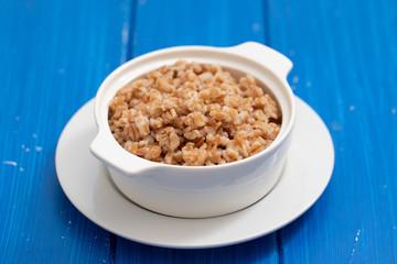 boiled spelt in white bowl on ceramic bckground