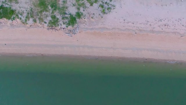 Tropical beach video loop showing seamless never ending footage with aerial bird eye view of green foaming ocean waves crushing against the coast line of Florida and overhead view of a seldom tourist