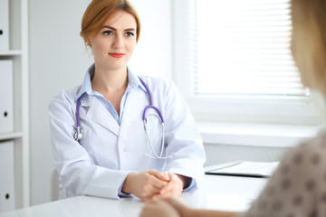 Doctor and patient discussing something while sitting at the desk at hospital. Medicine and health care concept