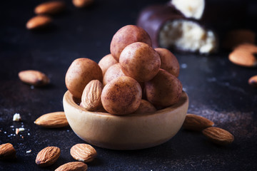 Marzipan, round almond candies in wooden bowl on dark table, selective focus