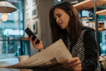 Beautiful young brunette looking at her phone in a coffee shop