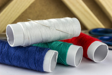 Colored spools of threads with a needle