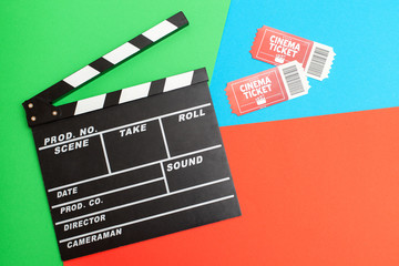 Fototapeta na wymiar A view from above of movie tickets and a movie clapper on a bright green-blue-red background with space for text. Movie time concept, Flat lay, Cinema background. Film watching