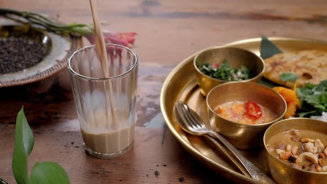 indian tea, masala tea, masala chai, herbal tea, spice tea with gujarati dahitra sweet pouring slow motion with carry traditional rice fish chicken