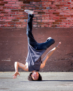 break dancer performing head stand freeze pose in secluded alley