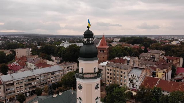 Tower of City Hall of Drohobych city with flag of Ukraine. Flight around the tower with a landscape on the city, overcast, autumn, Ukraine