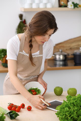 Young brunette woman cooking in kitchen. Housewife holding wooden spoon in her hand. Food and health concept
