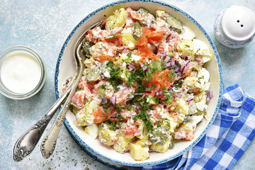 New potato salad with salted salmon, pickled cucumber, egg, capers and red onion.Top view.
