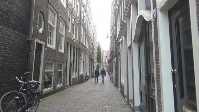 Two tourists walking between two houses in Amsterdam