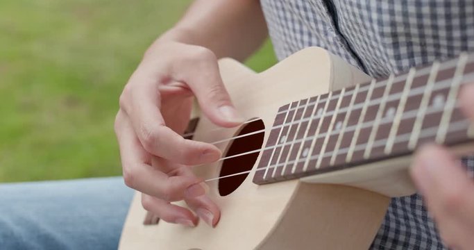 Woman play song on ukulele at outdoor