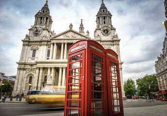 red phone boxes and yellow car passing Saint Paul's Cathedral in London at cloudy day
