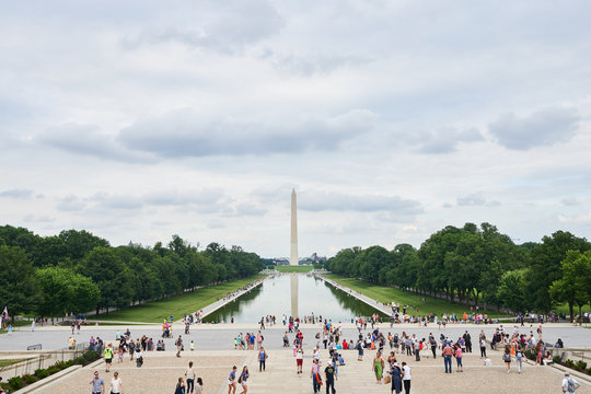 Crowds Of Tourists And People Near Reflecting Pool In Washington D.C. With The Washington Monument In The Background.