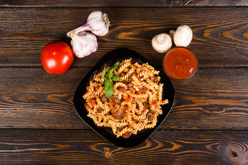 Pasta (spirals pasta)  Bolognese. Tagliatelle with minced meat  on a black plate on a dark wooden background