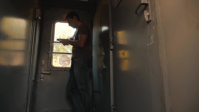 the man silhouette is standing on the train Railway carriage holding a smartphone and . slow motion video. man writes messages in the smartphone in the train social media. lifestyle man with