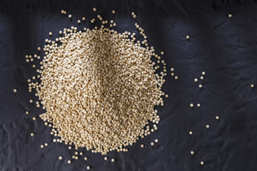 Quinoa grains with spoon and bowl on black background