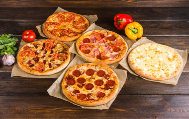 Small mini pizza (mini, miniature) on baking paper on a dark wooden background