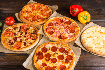 Small mini pizza (mini, miniature) on baking paper on a dark wooden background