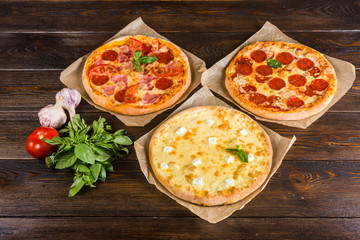 Small mini pizza (mini, miniature) on baking paper on a dark wooden background