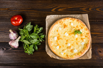 Small mini pizza (mini, miniature) on baking paper on a dark wooden background