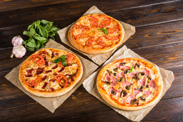 Small mini pizza (mini, miniature) on baking paper on a dark wooden background