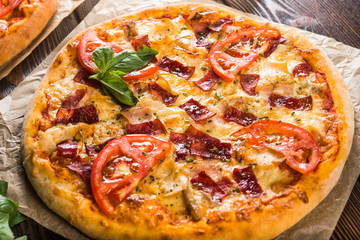 Small mini pizza (mini, miniature) on baking paper on a dark wooden background