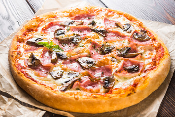 Small mini pizza (mini, miniature) on baking paper on a dark wooden background