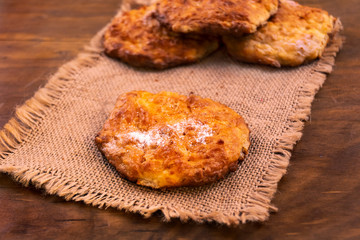 Round homemade cookies with ruddy crust on linen napkin, wooden background.