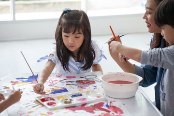group of Cute little girl student painting  together with nursery teacher in classroom school ....