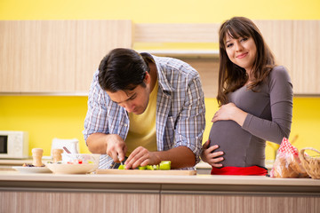 Obraz na płótnie Canvas Man and pregnant woman preparing salad in kitchen 