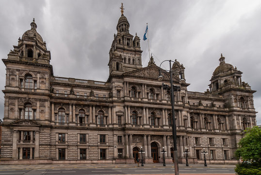 Glasgow, Scotland, UK - June 17, 2012: Frontal view on Brown stone Glasgow City Chambers building aginst dark cloudscape. 