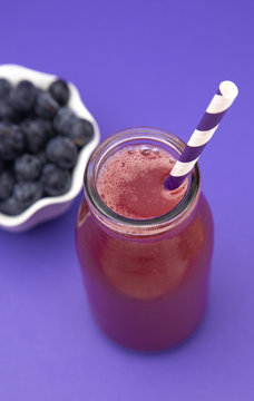 Berry Smoothie in a Glass Jug with a Straw
